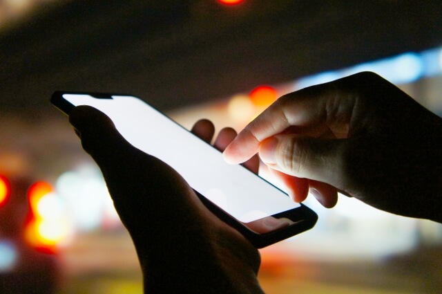 暗い場所でスマートフォンを操作する手